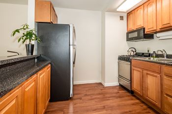 A kitchen with wooden cabinets and a fridge.at Garwood Gardens Apartments, New Jersey
